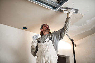 Worksman plastering gypsum walls inside the house.