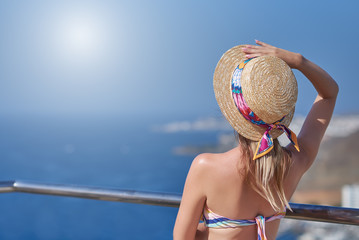 Young girl in bonnet hat is observing wonderful hotel’s view. Back view.