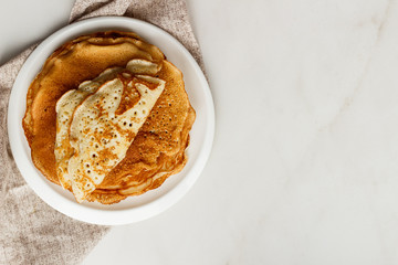 Staple of wheat golden yeast pancakes or crepes in a white plate closeup
