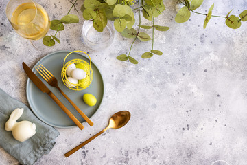 Happy Easter concept. Top view of beautiful spring table settings, plate with gold cutlery, easter...