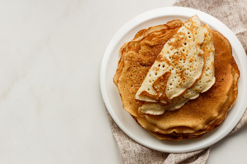 Staple of wheat golden yeast pancakes or crepes in a white plate closeup