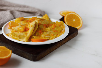 Traditional French crepes Suzette with orange sauce on white plate