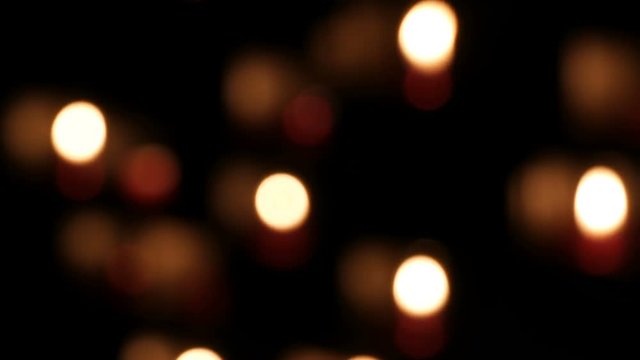 Beautiful blurred red church candles for prayers in special niches in a catholic temple on a black background