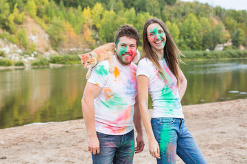 Pet, summer tourism, festival holi and nature concept - funny man and woman with cat on natural background
