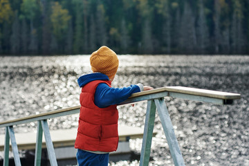 European boy is standing on the wooden bay and enjoying the view.