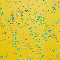 Colorful confetti on yellow background. Happy celebration concept. Flat lay