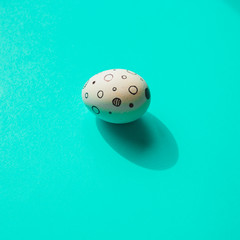 Easter egg with memphis style print on turquoise bright background with sharp shadows.  Happy spring holidays concept. Minimalism.