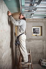 Workman plastering gypsum walls inside the house.