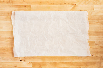 Crumpled piece of white parchment or baking paper on wooden table. Top view. Copy space for text...