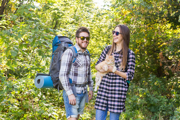 Travel, adventures, hike, tourism and nature concept - Tourist couple with cat walking in the woods