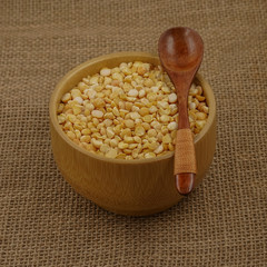 Raw yellow plate with wooden spoon and spoon against the background of burlap texture