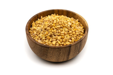 Raw yellow split peas in a wooden plate (bowl) isolated on white background