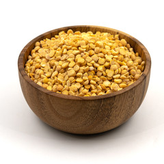 Raw yellow split peas in a wooden plate (bowl) isolated on white background
