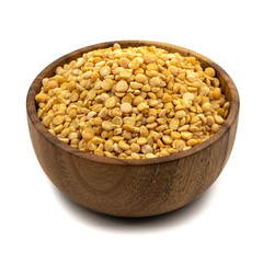 Raw yellow split peas in a wooden plate (bowl) isolated on white background