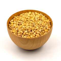 Raw yellow split peas in a wooden plate (bowl) isolated on white background