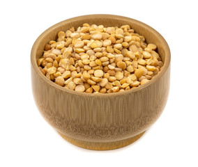 Raw yellow split peas in a wooden plate (bowl) isolated on white background