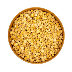Raw yellow split peas in a wooden plate (bowl) isolated on white background, top down view