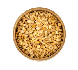 Raw yellow split peas in a wooden plate (bowl) isolated on white background, top down view