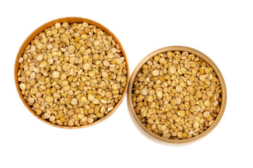 Raw yellow split peas in a wooden plate (bowl) isolated on white background, top down view