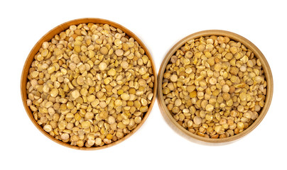 Raw yellow split peas in a wooden plate (bowl) isolated on white background, top down view