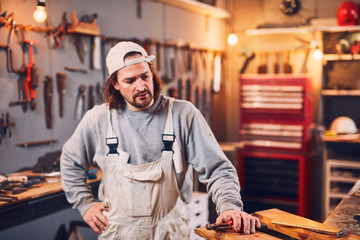 Male carpenter fixing old wood in a retro vintage workshop.