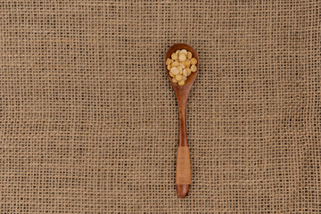 Wooden spoon with yellow  raw peas on a background of burlap texture
