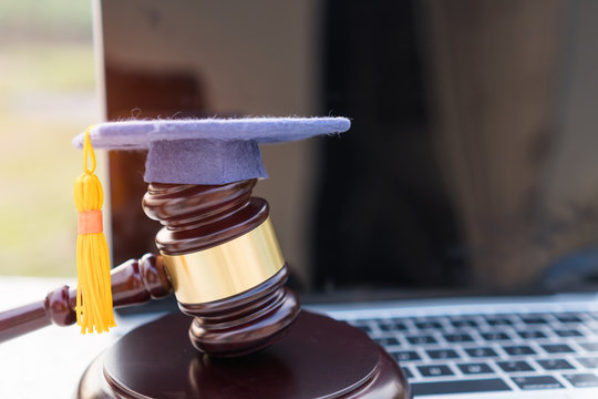 Concept of graduate online study international abroad about jurisprudence laws certificate in university distance education for learning. Graduation diploma hat / Judge gavel on computer notebook.