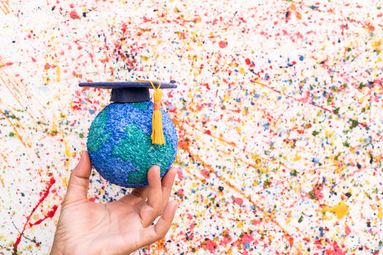 Education World Study Abroad Educational Knowledge Idea. Graduation Cap On Businessman Holding Paper Mache Craft Earth In Hand. Concept Of Graduate University On Water Colore Background,Back To School