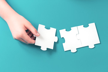 Jigsaw puzzle piece in a hand. Teamwork and solution or idea concept with copy space on trendy blue...