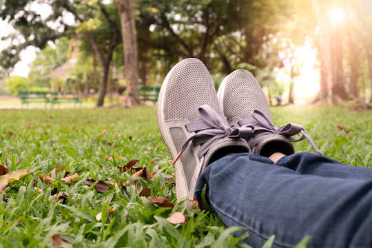 Woman feet in sneaker on green grass in the park