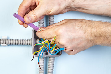 Worker twists wires with insulation shrinkable tube.