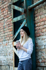 Close up portrait of a smiling young girl holding take away coffee cup outdoors. Beautiful woman holding paper coffee cup in the city