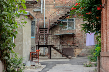Fototapeta na wymiar View of the old courtyard from the inside. Brick walls, green trees in the summer, a red chair and linen on the rope. Russia, Rostov-on-Don, the historic center of the city.