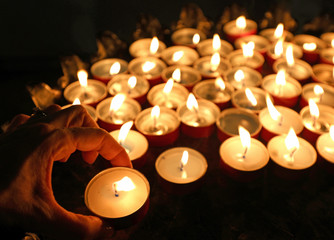 woman who puts a candle and recites a prayer of supplication to