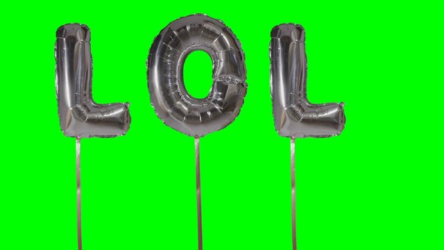 Word lol from helium silver balloon letters floating on green screen