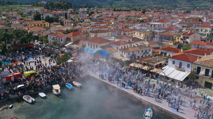 Aerial drone bird's eye view photo of people participating in traditional colourful flour war or Alevromoutzouromata part of Carnival festivities in historic port of Galaxidi, Fokida, Greece