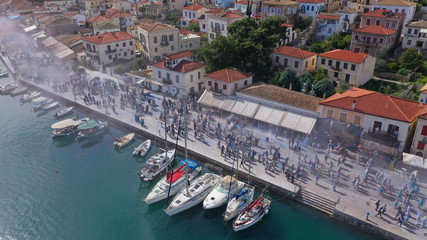 Aerial drone bird's eye view photo of people participating in traditional colourful flour war or Alevromoutzouromata part of Carnival festivities in historic port of Galaxidi, Fokida, Greece