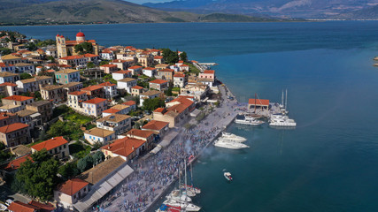 Aerial drone bird's eye view photo of people participating in traditional colourful flour war or Alevromoutzouromata part of Carnival festivities in historic port of Galaxidi, Fokida, Greece