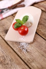 mozzarella cheese with fresh tomatoes and basil on a rustic wooden table 