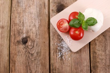 mozzarella cheese with fresh tomatoes and basil on a rustic wooden table 