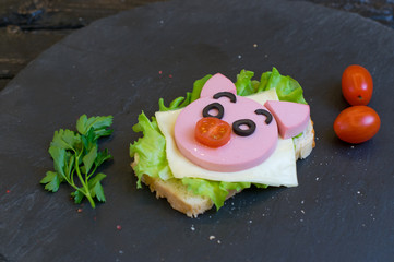 Children's sandwich with sausage made in the form of a pig. Option of children's serving