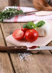 tomato mozzarella - fresh tomatoes with mozzarella cheese and basil  on a rustic wooden table