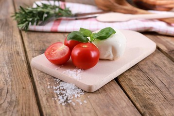 tomato mozzarella - fresh tomatoes with mozzarella cheese and basil  on a rustic wooden table