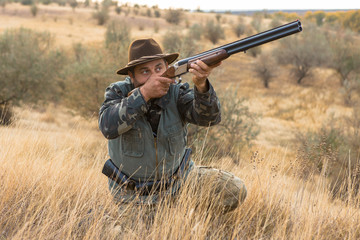 Hunter with a hat and a gun in search of prey in the steppe	