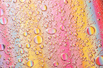 Beautiful macro photo of water droplets in oil with a colorful background.