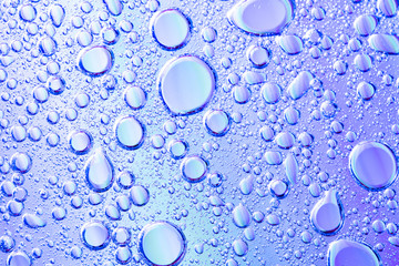 Beautiful macro photo of water droplets in oil with a violet background.