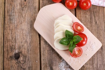 fresh tomatoes with mozzarella cheese and basil  on a rustic wooden table - healthy breakfast - top view