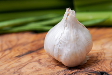 Organic Raw Whole Garlic bulb placed on natural olive wood. Allium sativum.
