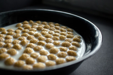 Bowl of cornflakes on dark background.