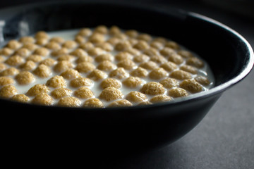 Bowl of cornflakes on dark background.